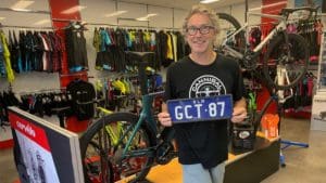 Glenn Forbes holds a custom Queensland number plate that’s part of the store’s memorabilia