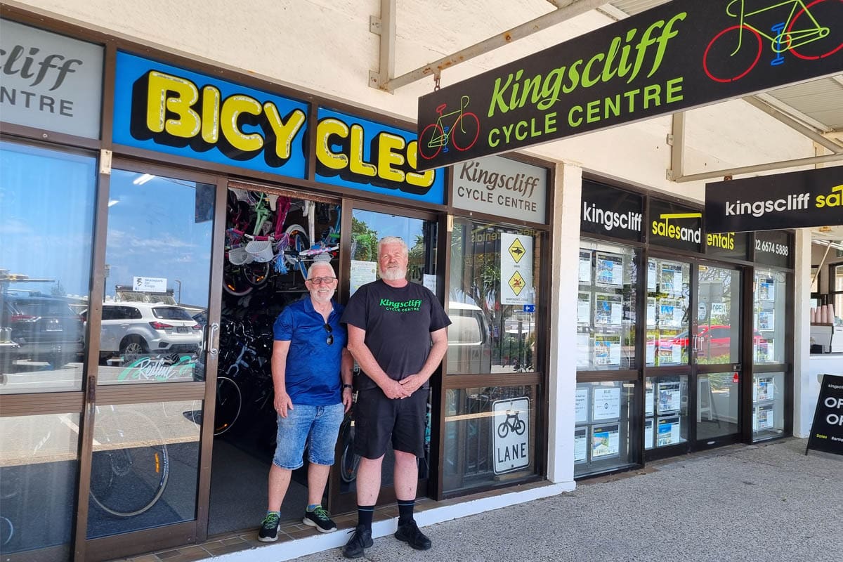 Two men standing in front of bicycle store