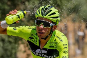 Cyclist squirting water on face with water bottle