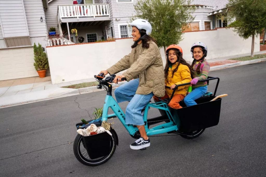 Woman riding e-cargo bike with children in the back