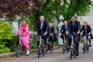 Team of people in professional attire riding bicycles.