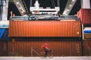person riding bike in shipping container yard