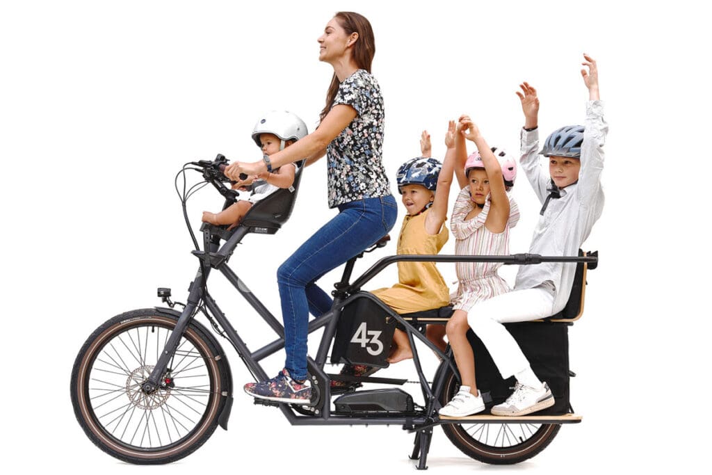 Woman riding e-cargo bike with four children