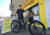 Man standing with bicycle out the front of bike shop
