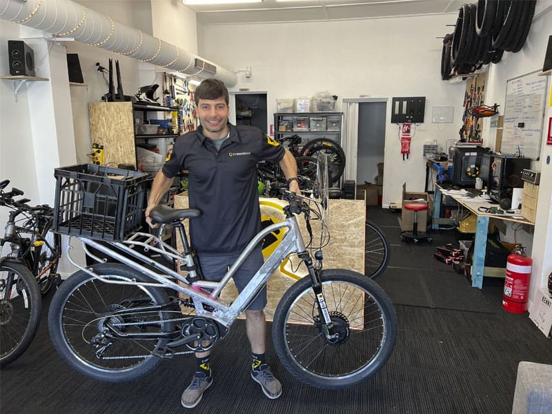 Man standing with bicycle inside bike shop