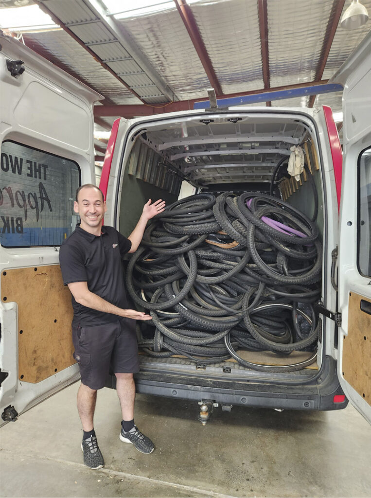A man standing with back of van full of used bicycle tyres