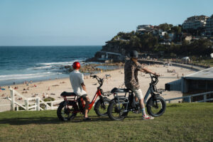 Two people on e-bikes overlooking beach