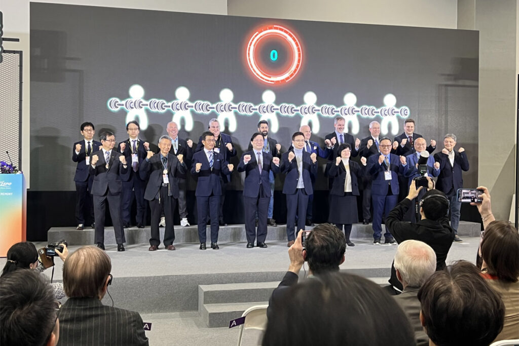 Group of people in business attire on stage posing for photographs.
