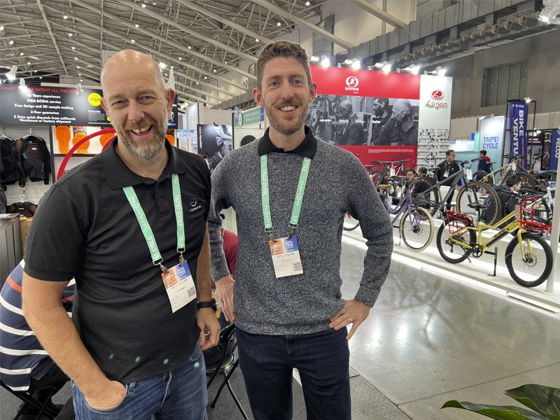 Two men standing in bicycle expo auditorium