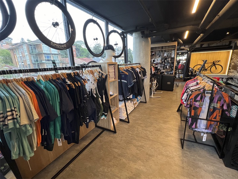 Interior view of bicycle shop, apparel products hanging on racks.