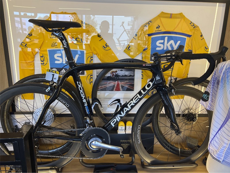 Bicycle on display in bike store with framed jerseys in background