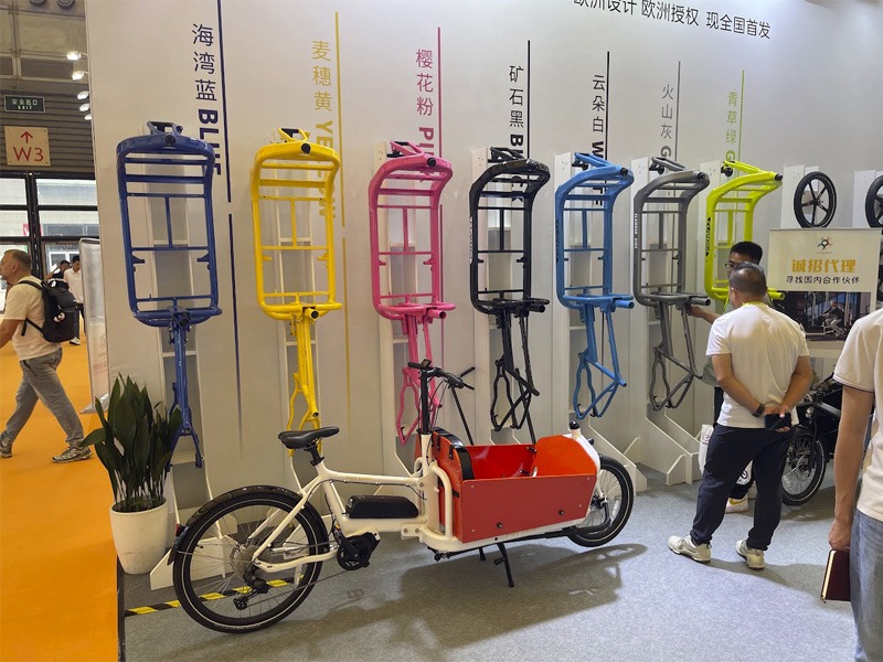Cargo bike on display with different colour options mounted to the wall
