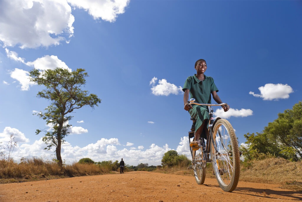 South African schoolgirl riding bicycle on a dirt track
