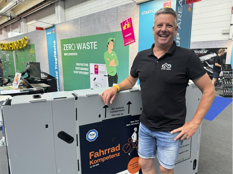 Man standing with bicycle box on display at expo