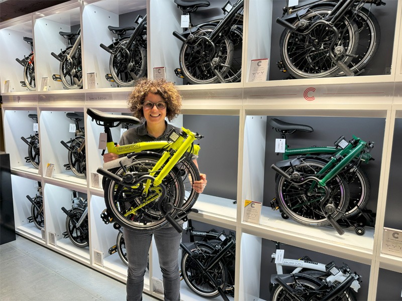 Woman in bike store holding a folded bicycle