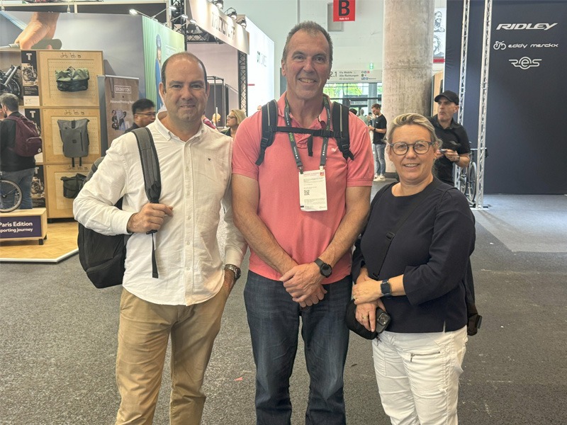 Three people standing in exhibition hall of bicycle expo