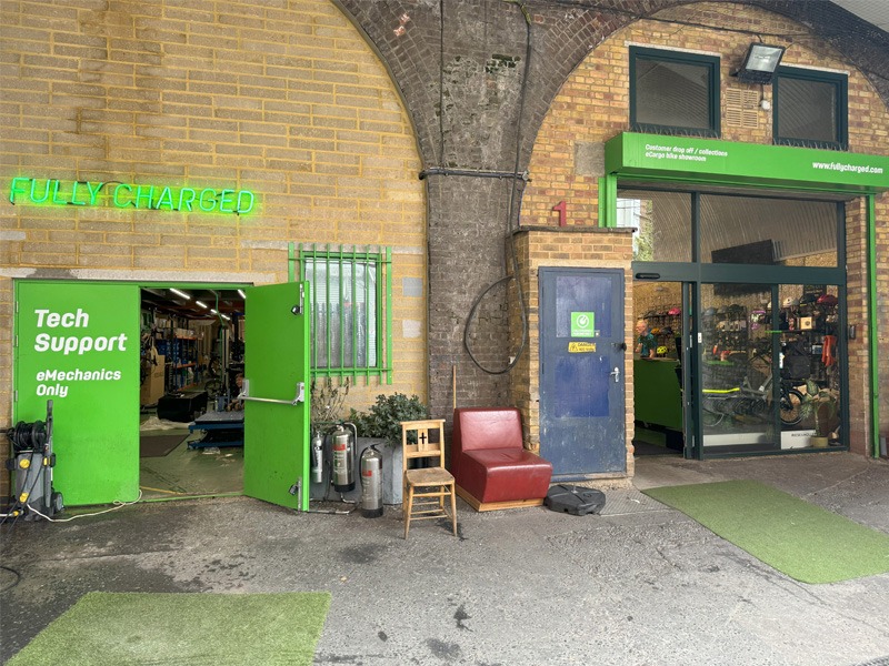 Large brick wall entrance to bicycle shop with neon green signage