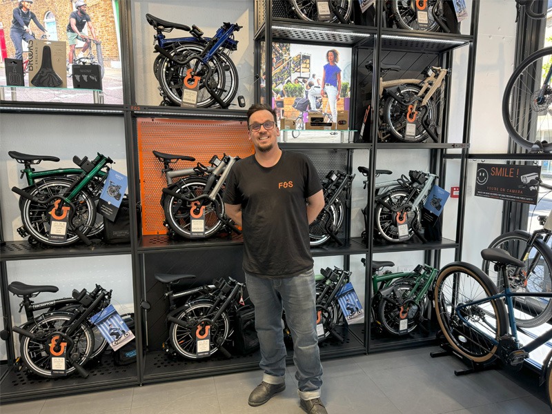 A man standing in front of a display of folding bicycles.