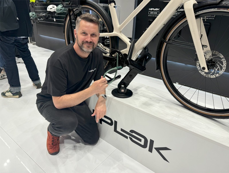 Man posing with bicycle attached to a lock at bike expo.