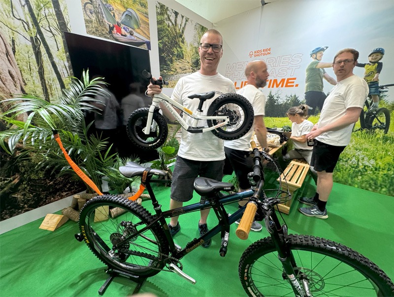 Man standing with a kids balance bike and an adult's bicycle at bike expo