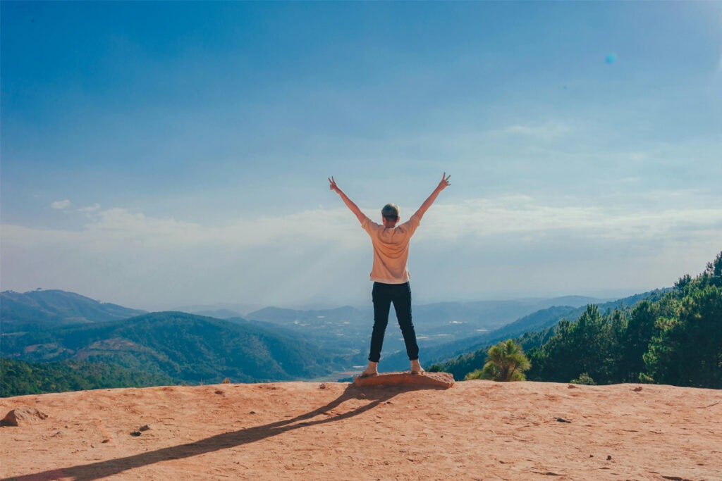 Person with arms in air with mountain background