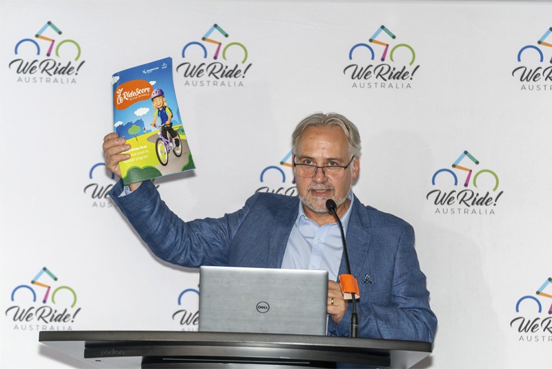 Person standing at a lectern holding up a report.