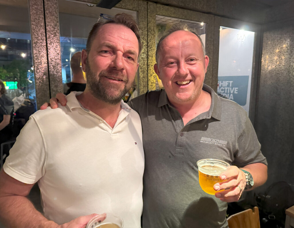 Two men, one holding a glass of beer