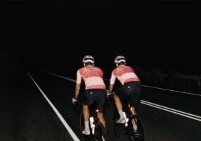 Two people riding on road at night