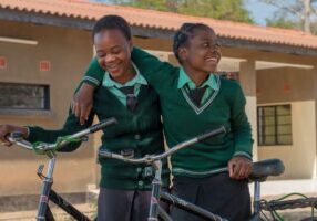 Two South African teenage schoolgirls with bicycles.